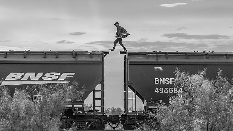 Un migrant camina sobre una mercaderia tren conegut com "La Bèstia" a Piedras Negras, Mèxic. Migrants i sol·licitants d'asil manca de recursos econòmics pagar a un contrabandista recorre sovint utilitzar trens de càrrega per arribar la frontera dels Estats Units. Això manera de transport és molt perillós; al llarg dels anys, centenars han caigut a la rastres i han estat assassinats o mutilat. Milers més han estat víctimes d'extorsió, violació, segrest o robatori orquestrada pels càrtels de la droga o autoritats corruptes en diversos parades al costat del tren ruta cap al nord.