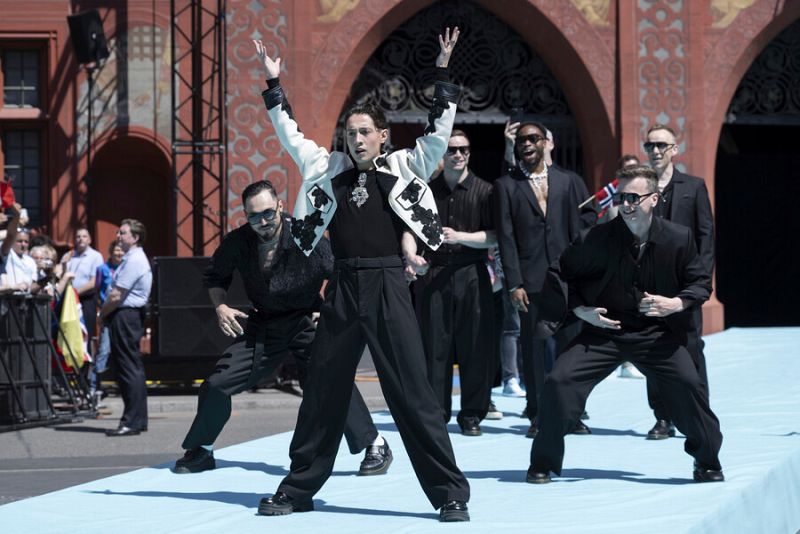 Delegación noruega en la Alfombra Turquesa de Eurovisión 2025.  Atuendos elegantes, mayormente negros con detalles blancos.  Posan para las cámaras.