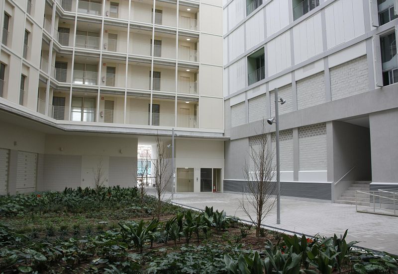 Patio ajardinado de edificio con fachadas, balcones, ventanas, puertas, trasteros, ascensor y rampa de acceso para personas con movilidad reducida.