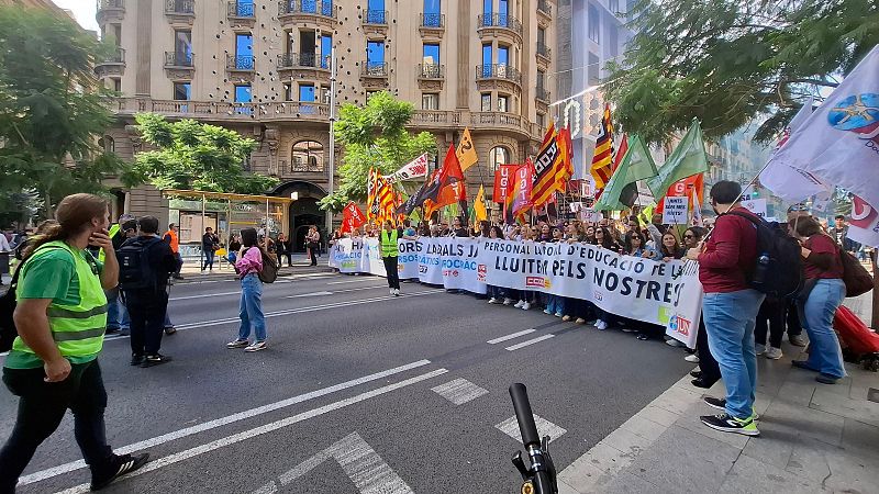 Milers de docents es manifesten a Barcelona, mostrant pancartes i banderes sindicals en un carrer amb edificis clàssics i arbres.