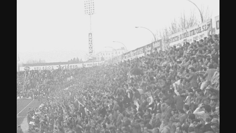 Vista panorámica de un estadio repleto de gente, con pancartas publicitarias y un letrero "AZOR". La imagen histórica, en blanco y negro, muestra el periodo 1962-1967.
