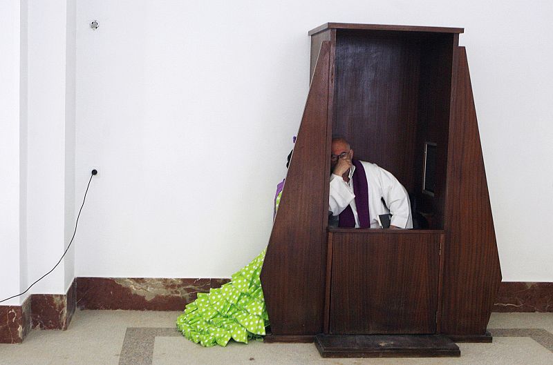 Una mujer se confiesa ante un sacerdote en la aldea del Rocío.