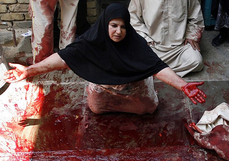 A woman reacts on a pavement covered with blood, after a relative was shot dead by a sniper, in Baghdad's Obaidi district