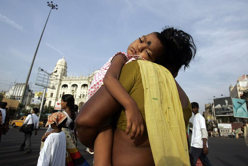 An HIV/AIDS-infected girl is carried by her mother to attend a peaceful rally to observe the Global AIDS Week of Action in Kolkata
