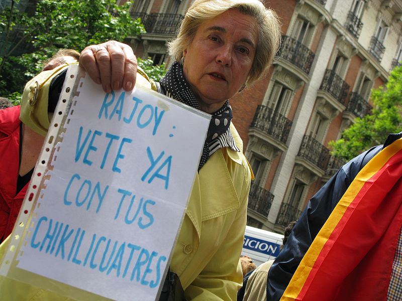 En una concentración ante la sede del PP, una señora porta un cártel pide a Rajoy que se vaya con sus "chikilicuatres".