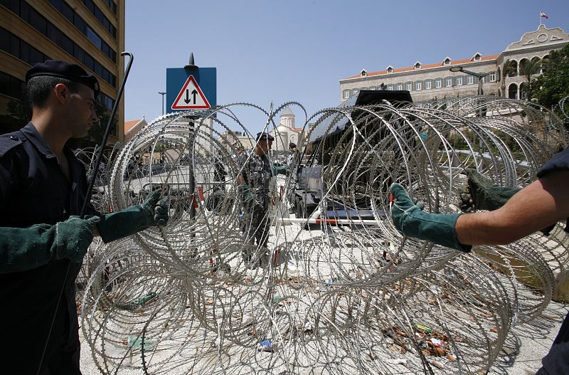 Lebanese policemen remove razor wires from a Hezbollah protest encampment in front of the government building in central Beirut