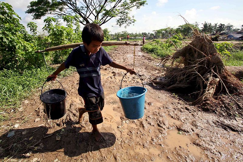 UN NIÑO TRANSPORTA DOS CUBOS CON AGUA EN LAS AFUERAS DE LA CIUDAD DE YANGÓN, BIRMANIA