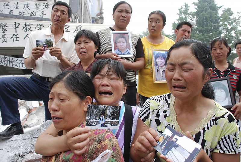 Unos padres sostienen el retrato de sus hijos muertos en una escuela en la provincia de Sichuan.