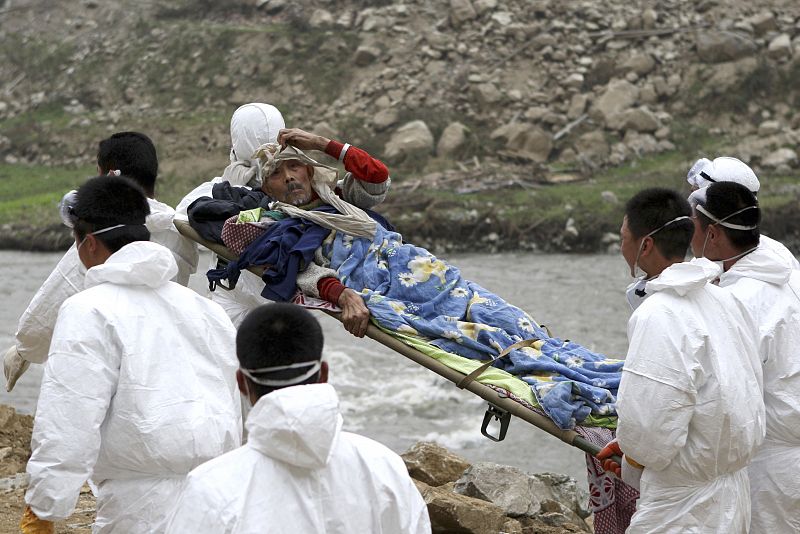 Soldados llevan a un hombre herido a un lugar más seguro en la localidad de Yingxiu, en el condado de Wenchuan.