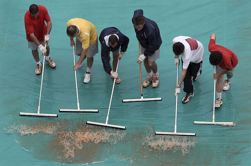 Varios empleados del Torneo retiran el agua acumulada en las lonas que protegen las pistas, durante la tercera jornada del Torneo Internacional de Tenis Roland Garros de París en la que la lluvia ha sido la protagonista.