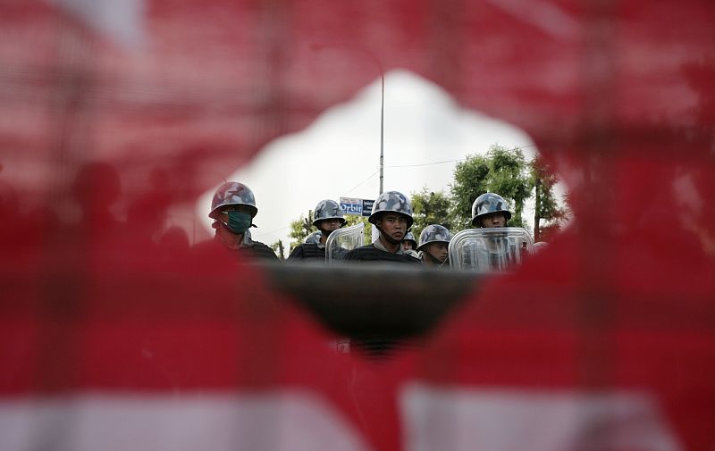 Policias armados custodian el parlamento de Nepal vista bajo el prisma de una bandera.