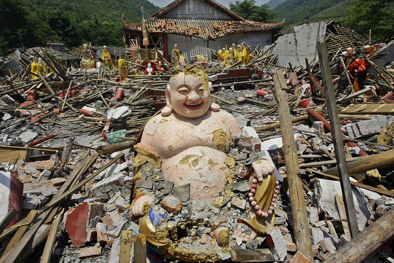 A damaged statue of Buddha is seen at the destroyed Xiayuan Temple in Luoshui town of earthquake-hit Shifang county