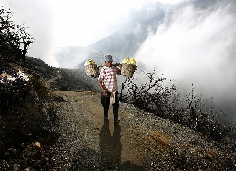 A miner carries a load of sulphur out of Kawah Ijen volcanic crater