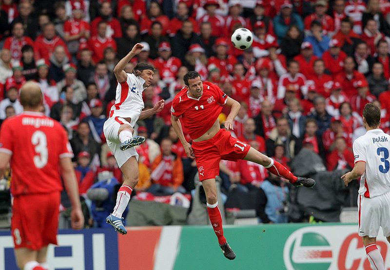 El jugador checo David Rozehnal salta por el balón con el suizo Marco Streller.