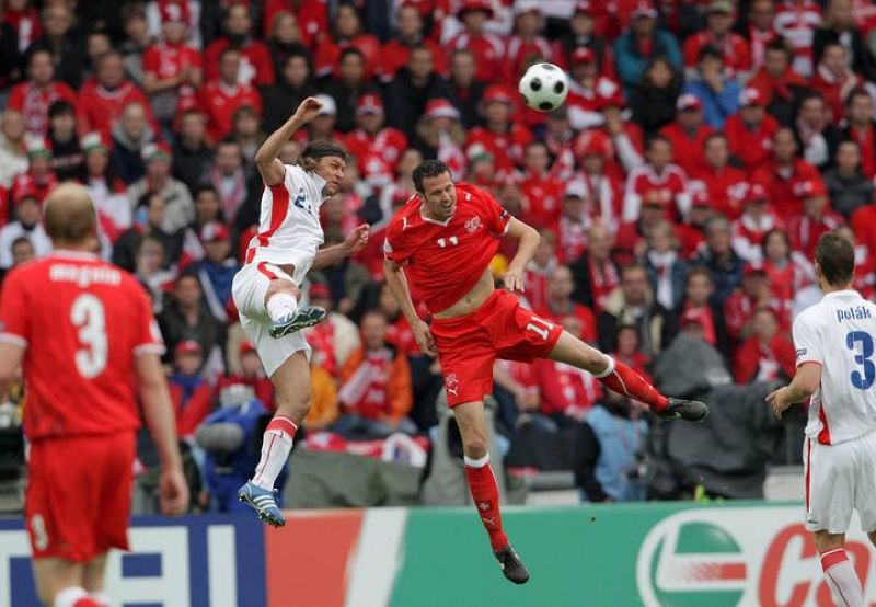 El jugador checo David Rozehnal salta por el balón con el suizo Marco Streller.