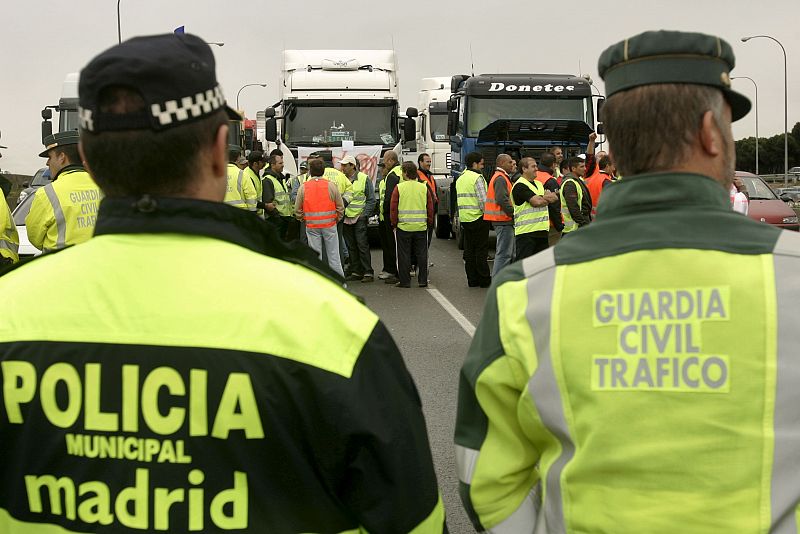 Miembros de las fuerzas de seguridad vigilan en la carretera de Burgos, en Madrid, cortada por un grupo de transportistas con motivo de la huelga.