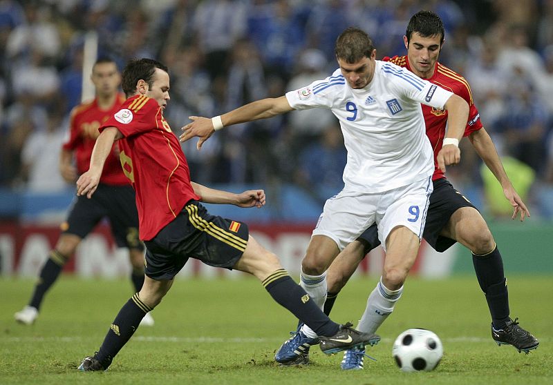 El delantero de la selección griega Angelos Charisteas lucha un balón ante los jugadores españoles Andrés Iniesta y Raúl Albiol.