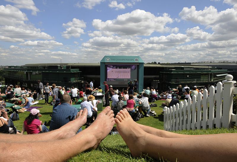 Los espectadores de Wimbledon disfrutan del buen tiempo de Londres viendo por una pantalla gigante los partidos de la primera jornada del torneo.