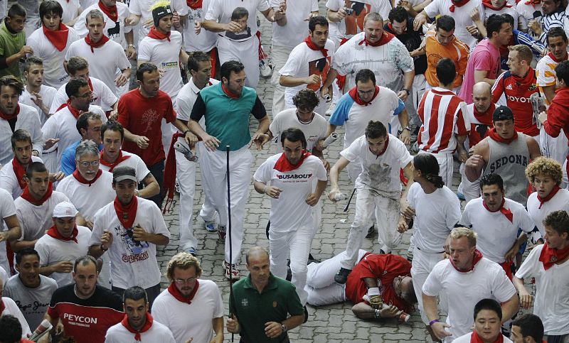 Runners look at fallen runner as they approach the bullring during the fourth bull run of the San Fermin festival in Pamplona