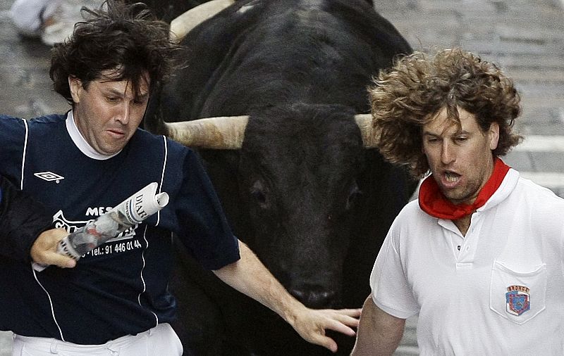 Runners are chased by bulls during the fifth bull run of the San Fermin festival in Pamplona