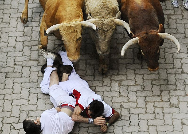 Runners fall in front of Nunez del Cuvillo ranch bulls during the last bull run of the San Fermin festival in Pamplona