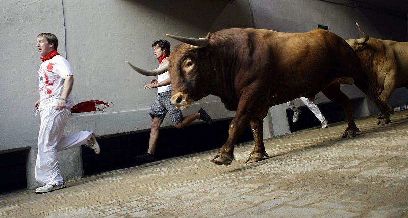 Runners are chased by Nunez del Cuvillo ranch bulls during the last bull run of the San Fermin festival in Pamplona