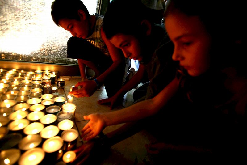 Varios niños israelíes encienden velas cerca de la casa de Eldad Regev el día en que han llegado a Israel los ataúdes con sus restos mortales desde el Líbano.