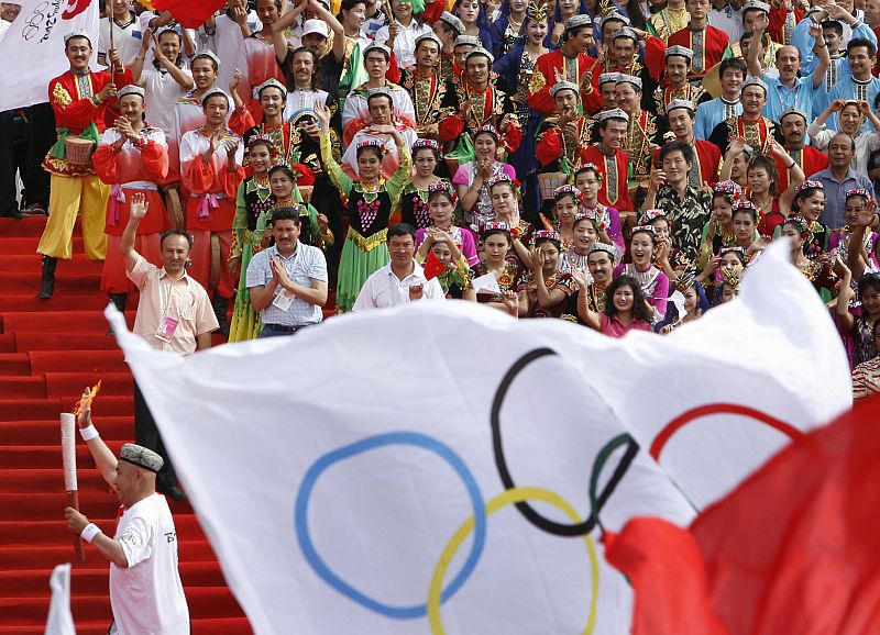 Un portador de la antorcha corre delante del animado público, durante el relevo en la ciudad de Kashgar (China)