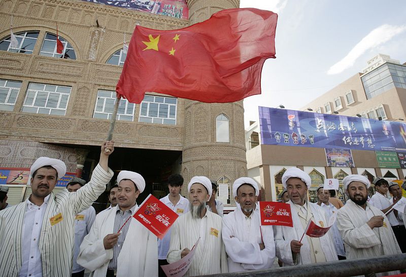 Clérigos musulmanes ondean banderas durante el paso de la antorcha en Kashgar (China)