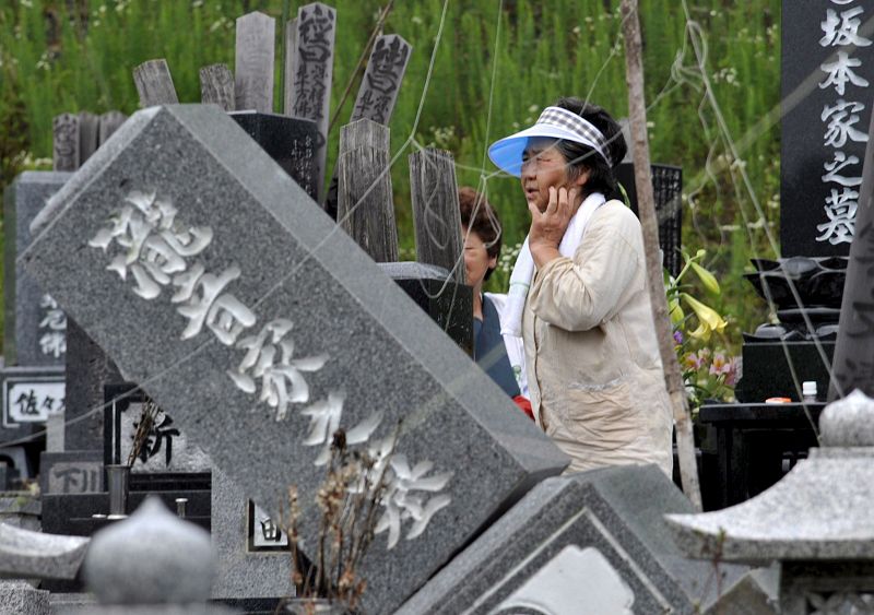 Una anciana camina entre lápidas dañadas en un cementerio en el norte de Japón, el 24 de julio de 2008, tras un fuerte seísmo de 6,8 grados.