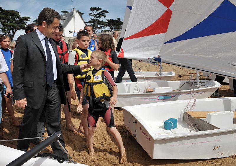 -France's President Nicolas Sarkozy speaks with children as he visits a holiday camp in Batz-sur-Mer