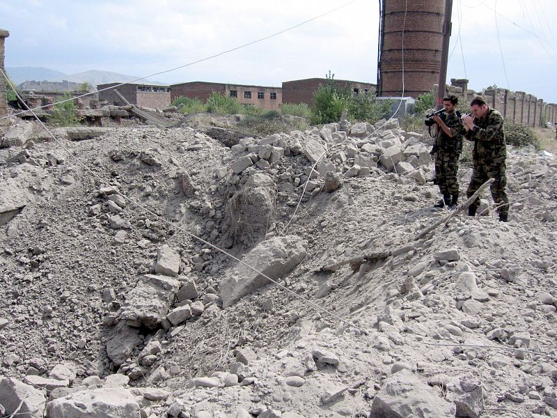 Dos militares georgianos toman imágenes del agujero que ha dejado una bomba lanzada desde un avión en la ciudad de Gori (Georgia).