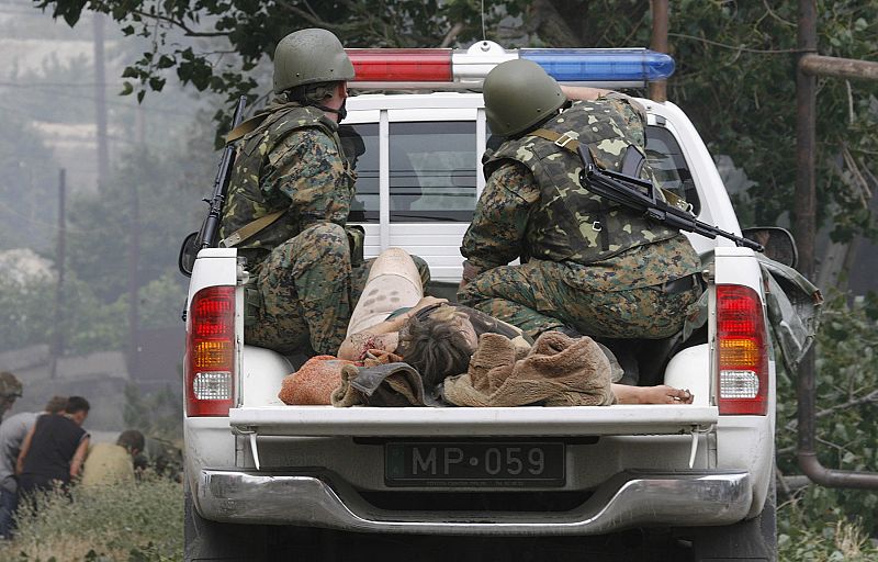 Georgian soldiers transport a dead body in the town of Gori