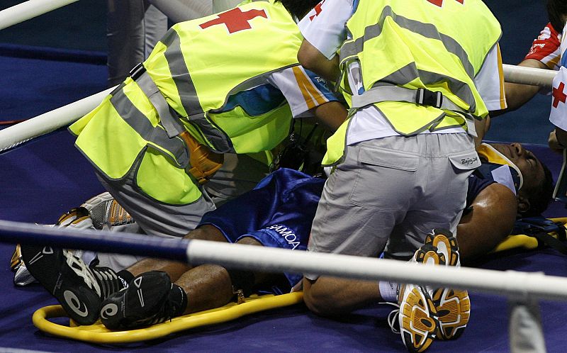 Farani Tavui de Samoa es atendido tras recibir un duro golpe de su contrincante croata en la competición de boxeo de peso semipesado.