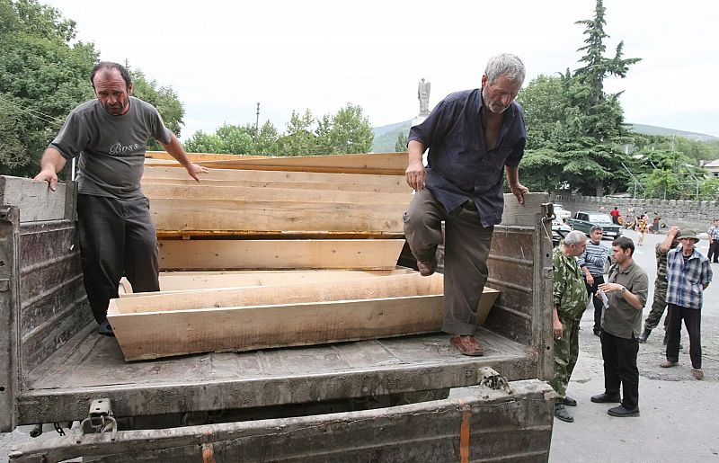 Hombres georgianos, detenidos por la milicia de Osetia del Sur, descargan ataúdes del furgón de un camión hoy, 15 agosto de 2008, en Tskhinvali (Georgia). Las autoridades de Osetía del Sur declararon que aproximadamente el 80 por ciento de la poblaci