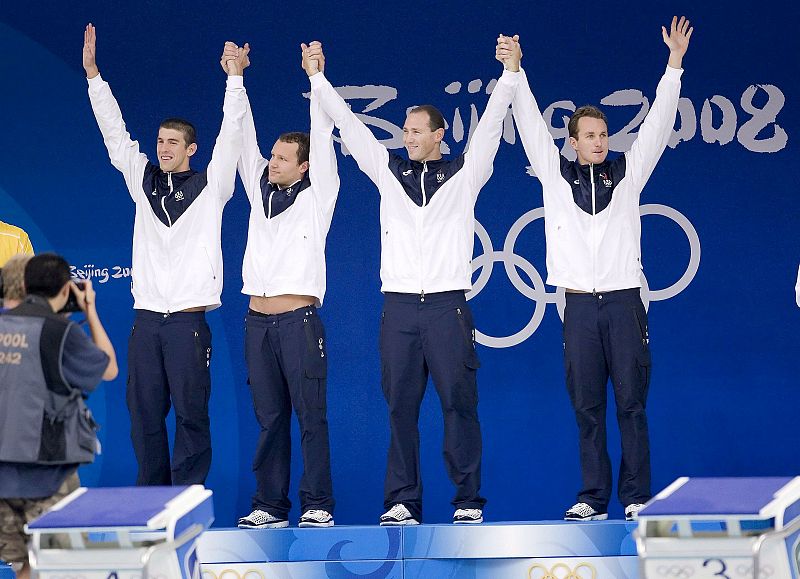 El nadador estadounidense Michael Phelps y sus compañeros de equipo, Brendan Hansen, Jason Lezak y Aaron Piersol celebran en el podio la medalla de oro en la prueba de relevos 4x100 y batir con 3:29.34 el récord del mundo.