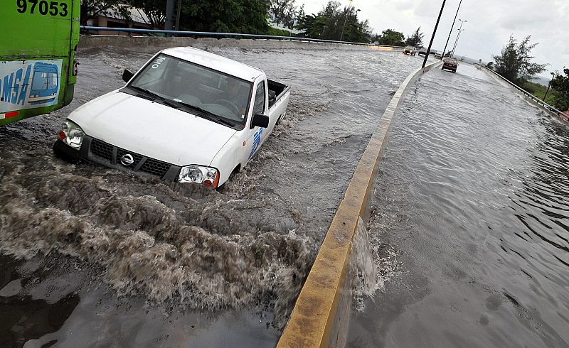 Varios vehículos circulan por una avenida inundada en Santo Domingo  producto de las fuertes lluvias que ha ocasionado a su paso la tormenta tropical 'Fay'