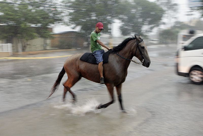 Un joven galopa su caballo bajo una intensa lluvia en la localidad de Higuey en República Dominicana