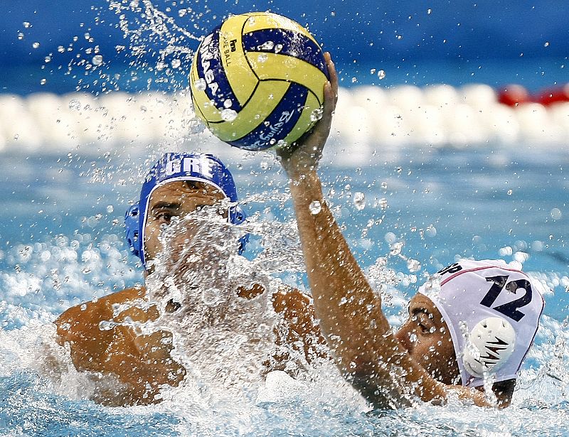 El español Javier García atrapa un balón ante la presión del griego Emmanouil Mylonakis en el partido de primera ronda de waterpolo.