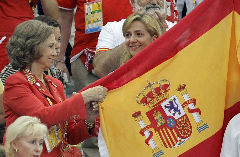 La reina Sofía y la infanta Cristina depliegan una bandera de España antes de celebrar la medalla de plata que ganaron las españolas Gemma Mengual y Andrea Fuentes.