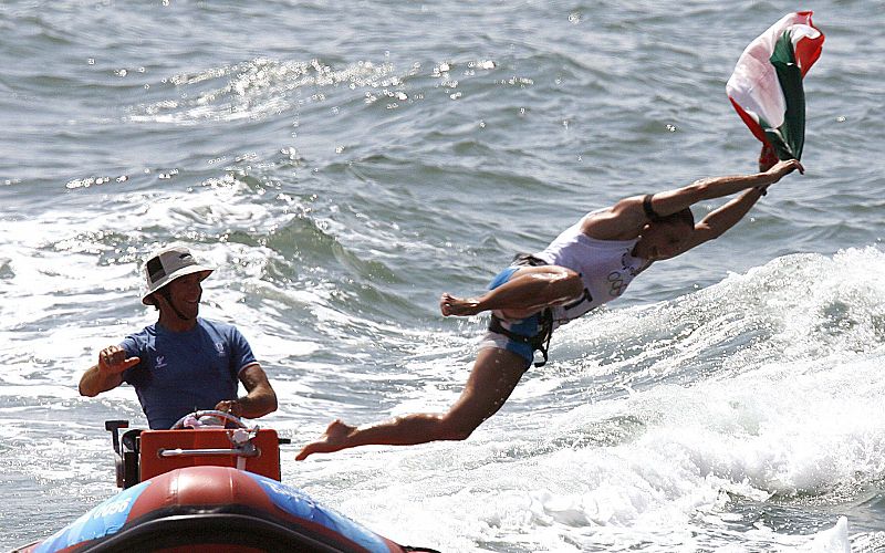 La deportista italiana Alessandra Sensini salta al agua desde un bote para celebrar su medalla de plata en la competición de windsurf RS:X femenino.