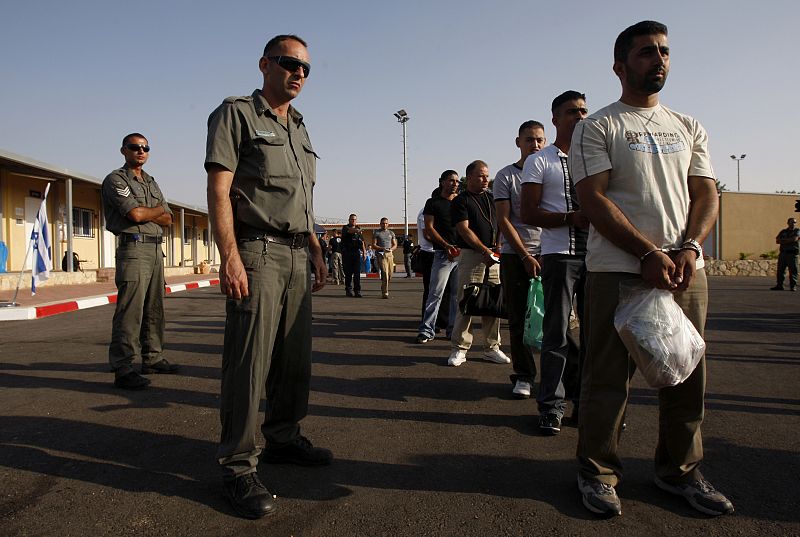 Israeli prison guards stand beside Palestinian prisoners at Ofer prison outside Ramallah