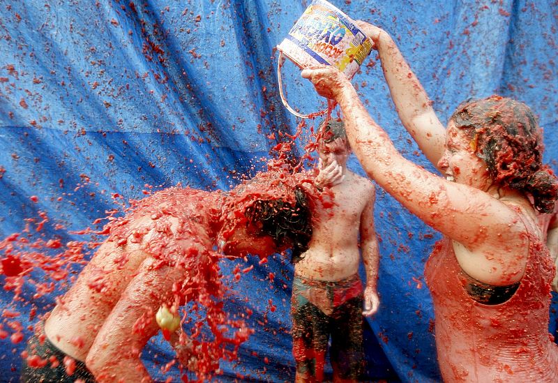 Un joven es rociado con tomate durante el festejo de Buñol, para el que se ha precisado la utilización de seis camiones para transportar estas hortalizas.