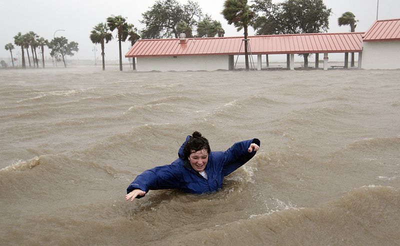 Una mujer intenta andar por una zona completamente inundada junto a un lago en Nueva Orleans.