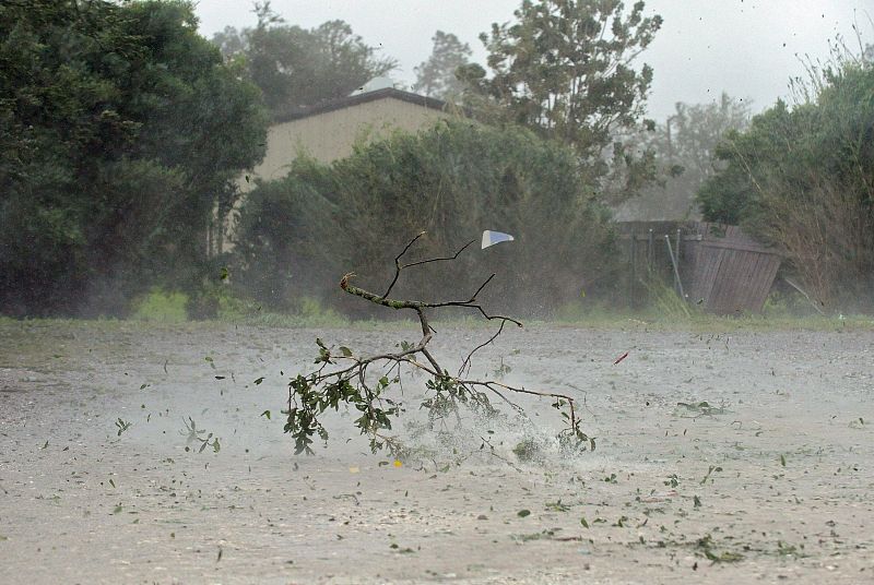 Ramas de árboles arrancadas por el viento, vuelan por una calle en Houma, Luisiana.