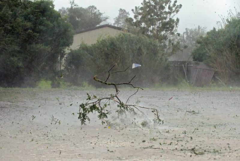 Ramas de árboles arrancadas por el viento, vuelan por una calle en Houma, Luisiana.