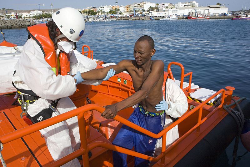 A would-be immigrant is helped by a rescue worker upon arriving at Arguineguin port in the Canary Islands of Gran Canaria