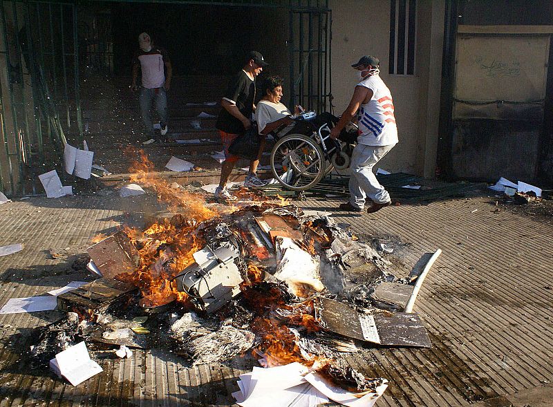 Un discapacitado es retirado de las oficinas estatales del Instituto para la Reforma Agraria (INRA) durante los enfrentamientos entre el ejercito y un grupo de universitarios y de la Union Juvenil Cruceñista.