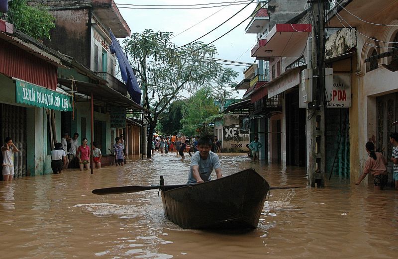 A resident pushes a boat along flooded road in Vietnam's northern Bac Giang province