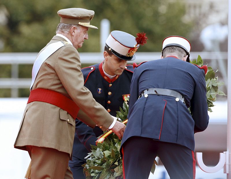 El Rey don Juan Carlos, junto a dos miembros de la Guardia Real, depositan una corona de laurel durante el homenaje a los que dieron su vida por España.